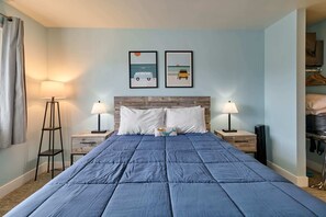Een hotelkamer met een groot bed, twee nachtkastjes met lampen, een houten hoofdbord, en twee ingelijste foto's aan de muur.
