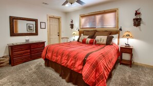 A bedroom with a large bed, a dresser, a ceiling fan, a window with blinds, and a nightstand with a lamp. - (36) Larkspur Lair at The Redwoods In Yosemite (Yosemite National Park)