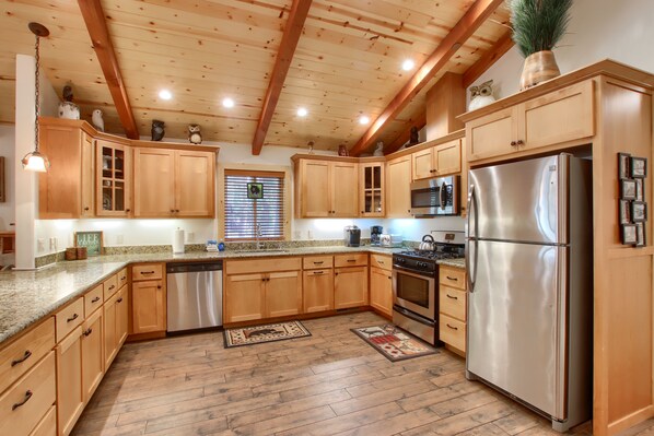 A kitchen with wooden cabinets, stainless steel appliances, and a wooden ceiling. - (36) Larkspur Lair at The Redwoods In Yosemite (Yosemite National Park)