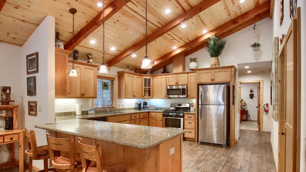 A spacious kitchen with wooden cabinets, granite countertops, and stainless steel appliances. - (36) Larkspur Lair at The Redwoods In Yosemite (Yosemite National Park)