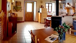 Una sala de estar acogedora con un sofá azul, una mesa de comedor de madera y un jarrón de flores.