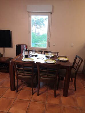 Enjoy dining with a view of lush greenery from this cozy dining area, complete with a round table for four and a flat-screen TV.