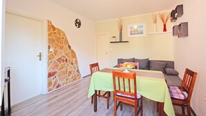 A dining area with a table set for two, a sofa, and a stone wall.