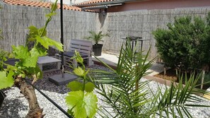 A patio area with a wooden bench, a table, and a potted plant. - Lovely apartments Korado 2 (Pula)
