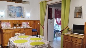 A cozy room with a wooden dining table, chairs, a television, and a cabinet. -  * RUNNING AND WALKING BEACH * enclosed garden * CLIM * WIFFI * PARKING * (Saint-Cyprien)