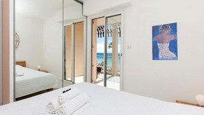 Habitació d'hotel amb llit, bany amb mirall i vista al mar.