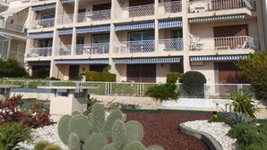 Hotel de diversos pisos amb balcons i un jardí paisatjistic ple de cactus.