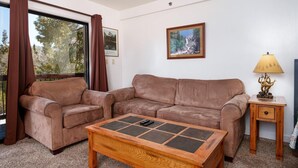 Ein Wohnzimmer mit braunem Ledersofa, einem Holztisch, einem gerahmten Bild an der Wand und einer Lampe auf einem Beistelltisch.
