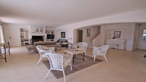 A spacious living room with a sofa set, white wicker chairs, a coffee table, and a piano. - Villa with private pool - 10 people - Sea view - Air conditioning - WiFi - Sainte Maxime - Rated 4* (STE MAXIME)