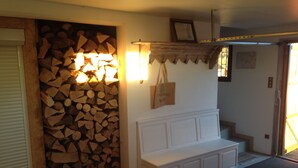 Ein Zimmer mit Holzstapel, einer weißen Bank und einem an der Wand befestigten Regal mit Tasche und gerahmtem Bild.