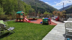 A playground with a slide and climbing structures, surrounded by a grassy area and a mountain backdrop. - The Best Place To Visit Como Lake (Barni (COMO))