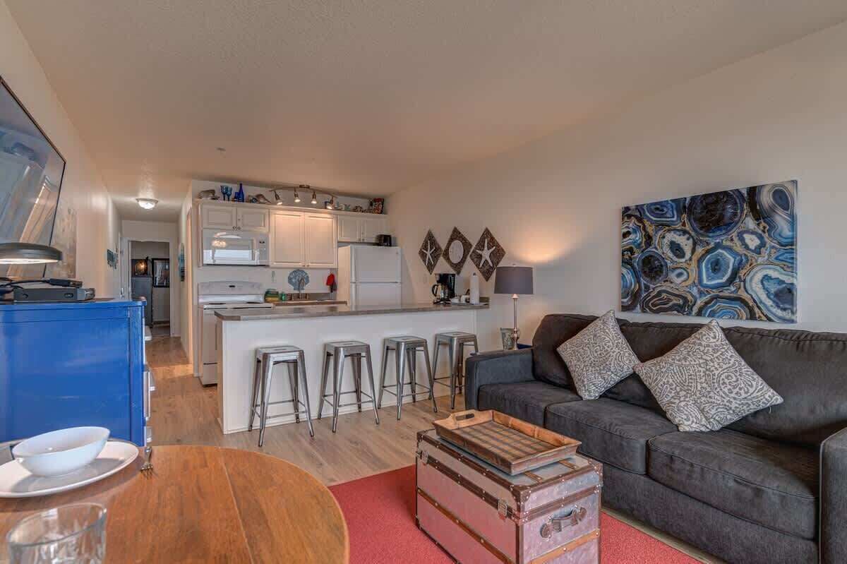A compact living space with a kitchenette, a dining area with a table and chairs, and a sofa with patterned cushions.