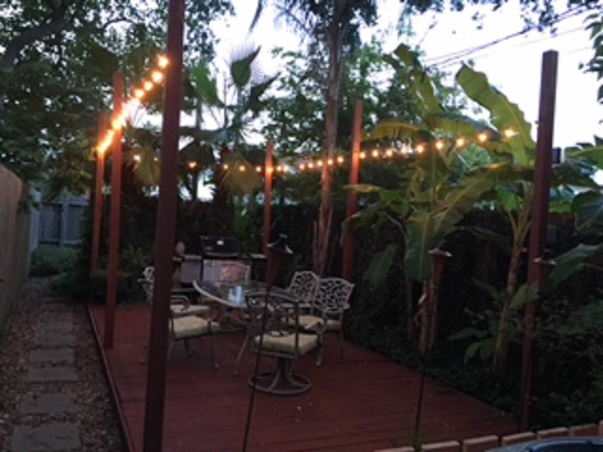An outdoor patio area with string lights, a table, chairs, and a wooden deck.