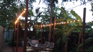 An outdoor patio area with string lights, a table, chairs, and a wooden deck.