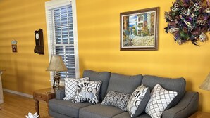 A living room with a sofa, a coffee table, and a wicker chair.