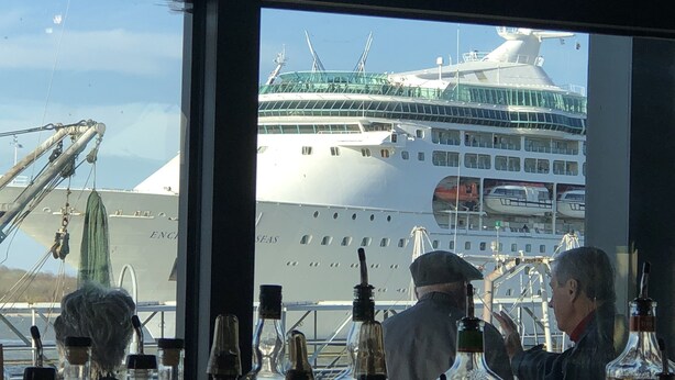 A large cruise ship docked at a port with visible deck structures and a person in uniform.