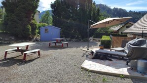 An outdoor patio area with picnic tables, a barbecue grill, and a small shed. - Atypical Cottage in the Chapel of the Miners (Sainte-Marie-Aux-Mines)