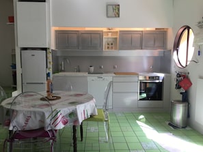 Compact kitchen with modern design, white cabinetry, stainless steel oven, sink, and dishwasher.