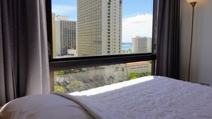 Une chambre d’hôtel avec une grande fenêtre, un lit et une vue sur de hauts immeubles.