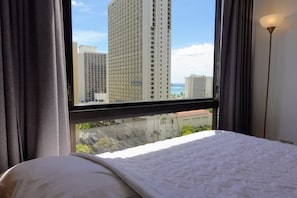 Een hotelkamer met een groot raam, een bed en uitzicht op hoge gebouwen.