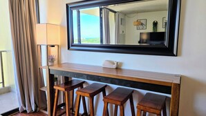 Une pièce dotée d’un grand miroir, d’une console en bois et de trois tabourets en bois.