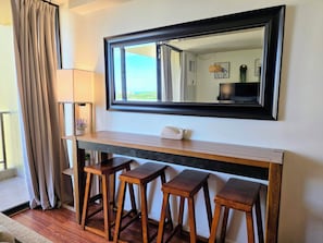 Een kamer met een grote spiegel, een houten console en drie houten krukken.