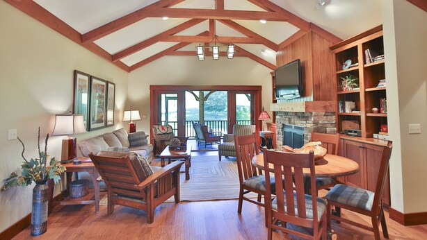 A spacious living room with wooden beams, a fireplace, a TV, and a dining area with chairs and a table.