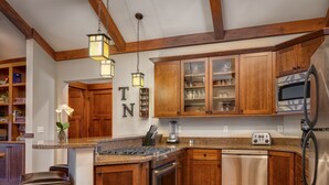 A kitchen with wooden cabinets, a stainless steel refrigerator, a microwave, and a built-in oven.