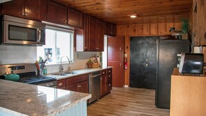 Una cocina con armarios de madera, electrodomésticos de acero inoxidable y un refrigerador negro.