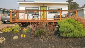 Una casa de un piso con un patio vallado, una puerta principal y un pequeño jardín con diversas plantas.