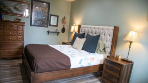 Un dormitorio ordenado con una cama de madera, un aparador y dos mesitas de noche con lámparas.