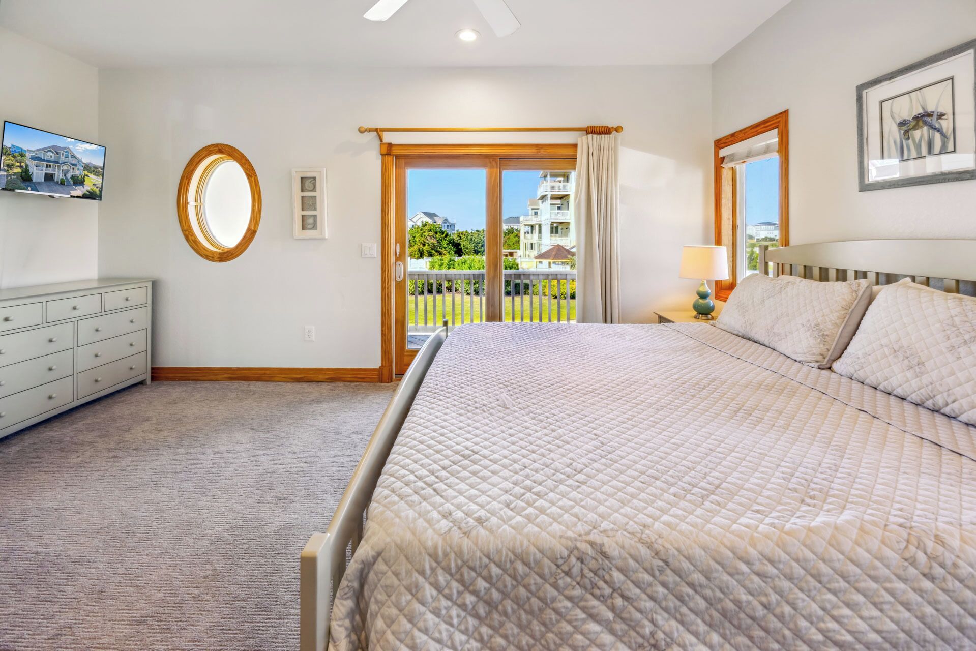 Une chambre à coucher avec un grand lit, une commode, un miroir rond et une vue sur l’extérieur.