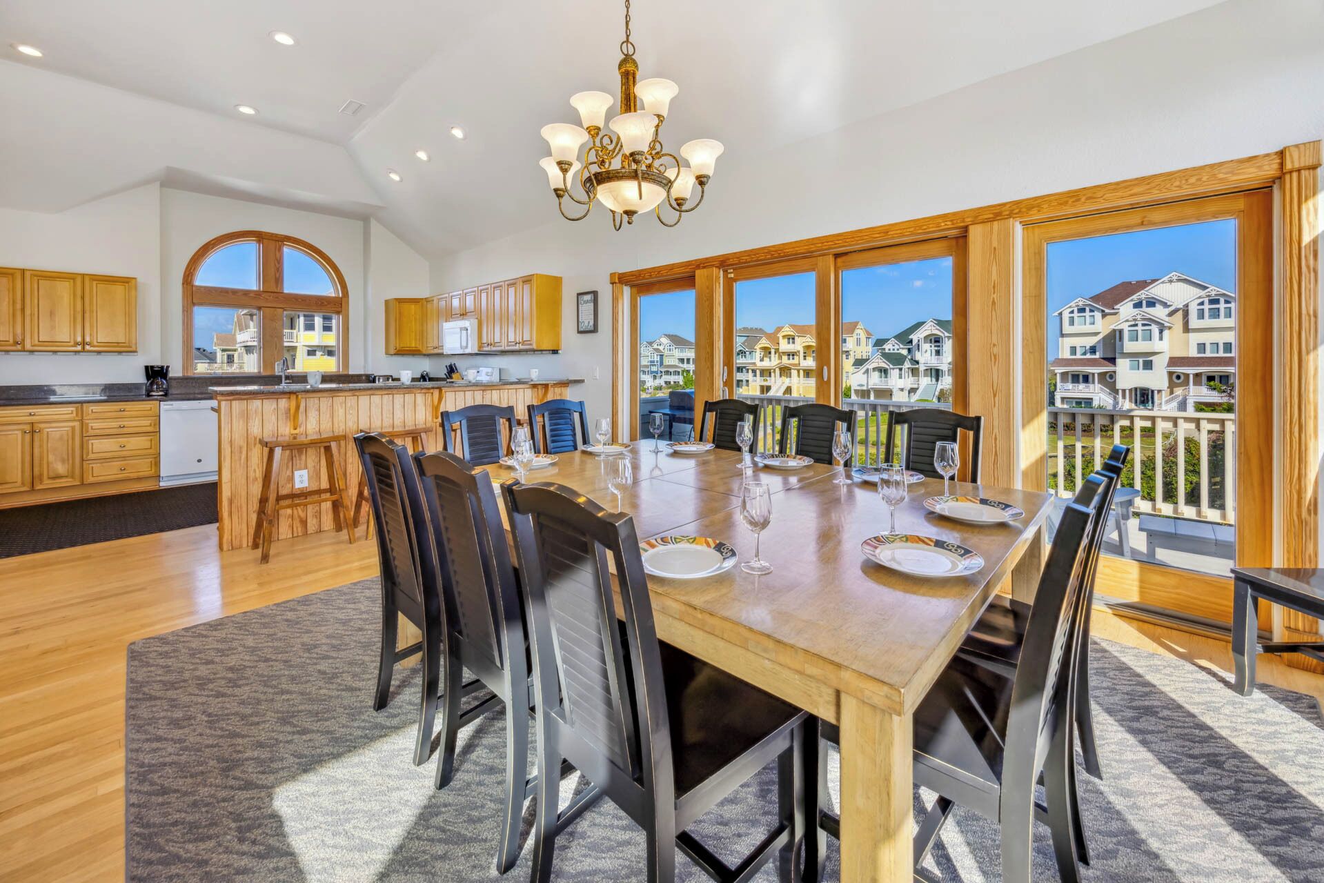 A spacious kitchen with wooden cabinets, a central island, and a large dining table set for six. - Oceanview Dog Friendly Home with Pool, Hot Tub, Elevator, Game and Media Rooms (Avon)