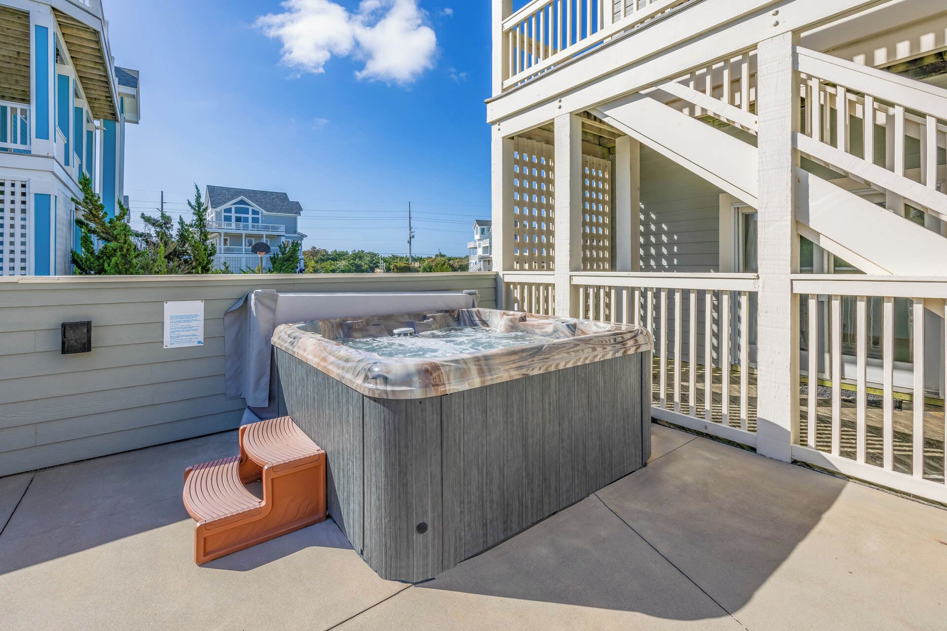 Un jacuzzi en un balcón con vistas a edificios cercanos.
