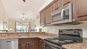 Eine moderne Küche mit Granit Arbeitsplatten, Edelstahlgeräten und Holzschränken.