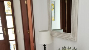 Un couloir avec une console blanche, une lampe, des bougies et une plante en pot.