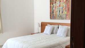 Une chambre à coucher avec un lit, un luminaire suspendu, un tableau au mur et une porte.