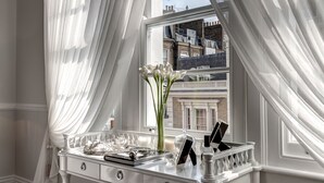 Une coiffeuse blanche avec un miroir, un vase rempli de fleurs et un plateau contenant des articles de toilette.