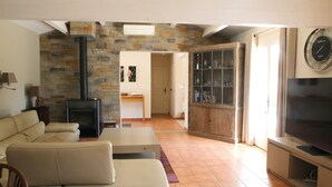 Una sala de estar con chimenea de piedra, un sofá, un televisor y un aparador con puertas de vidrio.