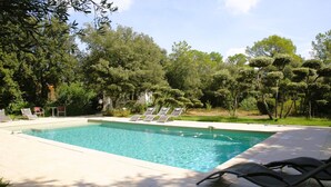 Una piscina rectangular con agua azul cristalina, rodeada por una solana con baldosas. Varias sillas de descanso están dispuestas a lo largo del borde de la piscina.
