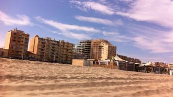 A sandy beach with buildings in the background.