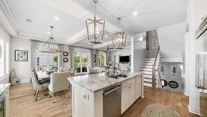 Una cocina amplia con una isla grande, modernas lámparas colgantes y vistas al exterior.