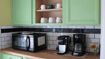Una cocina con gabinetes verdes, un microondas, una cafetera y una licuadora en la encimera.