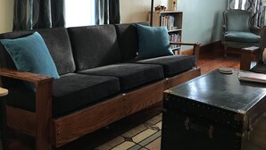 A cozy living room with a dark sofa, a wooden coffee table, and a patterned rug.