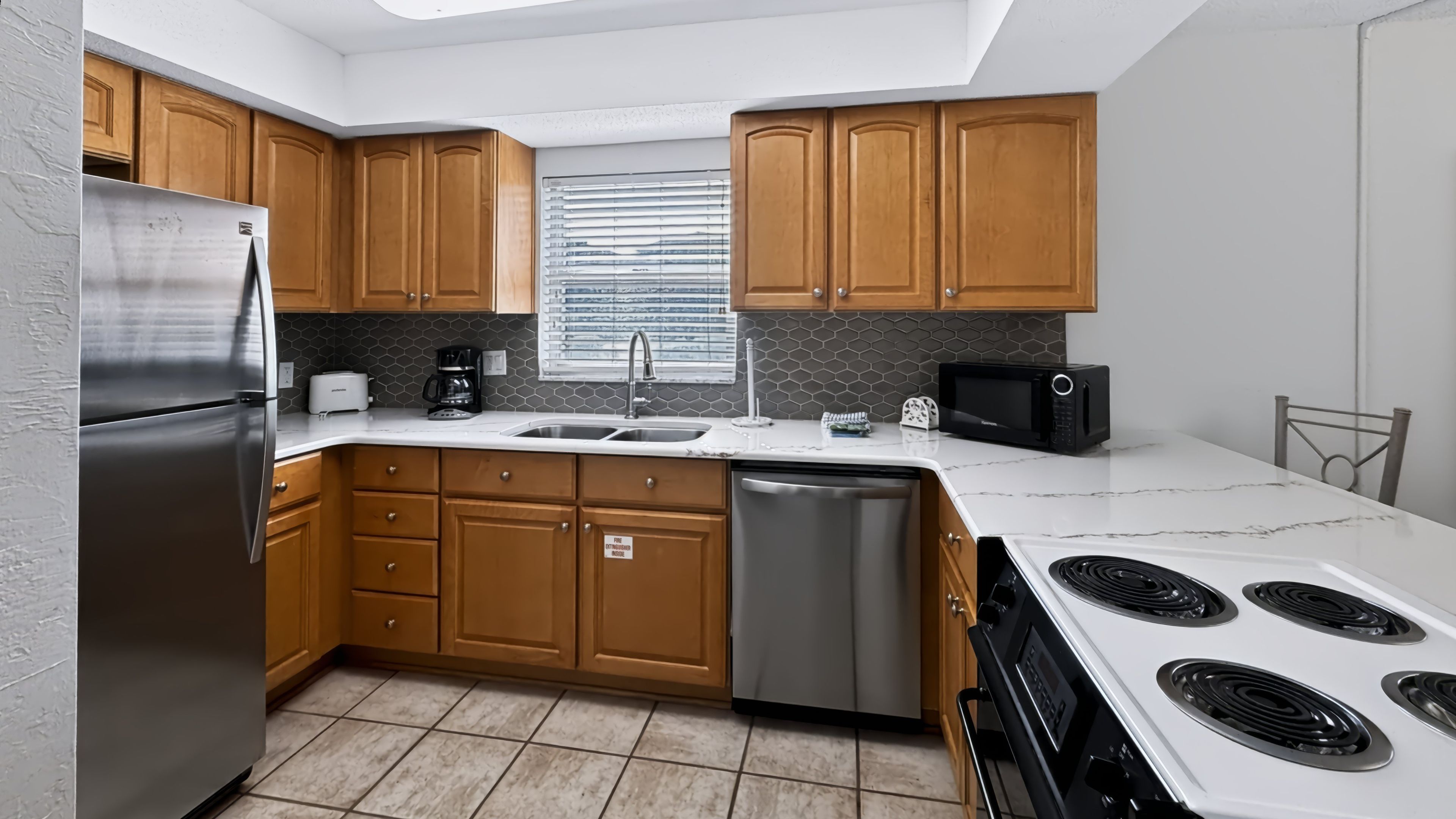 Una cocina moderna con armarios de madera, electrodomésticos de acero inoxidable, lavavajillas y microondas.