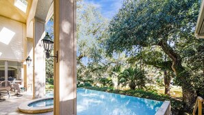 A swimming pool with a stone deck, surrounded by lush greenery and trees. - Luxury 6BR 3rd Row Home w/ Patio & Private Pool (Hilton Head Island)