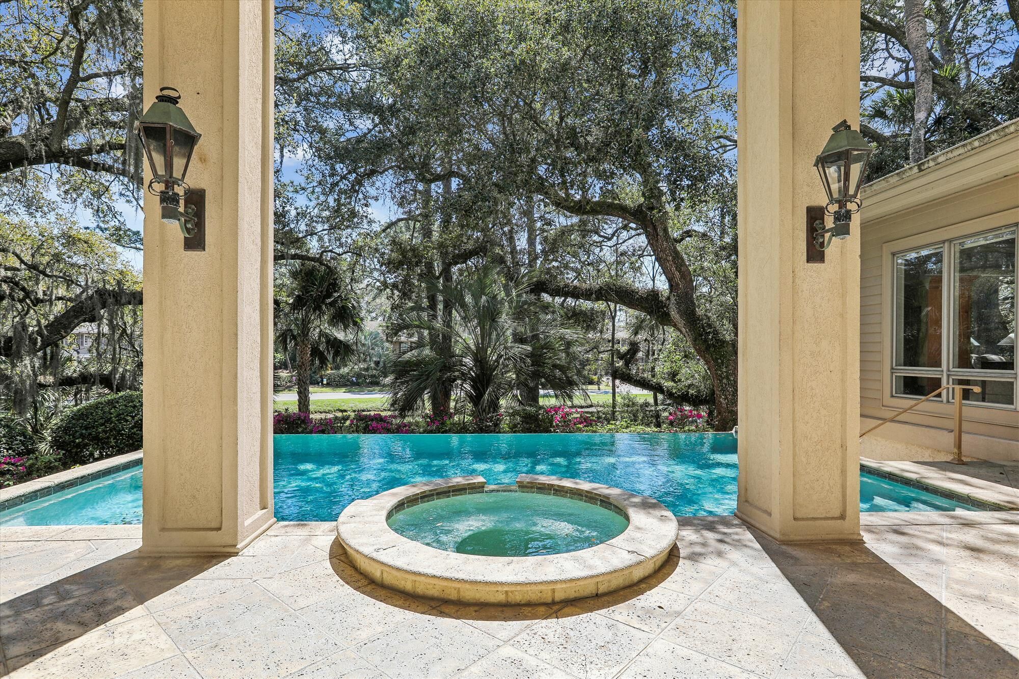 Un área de piscina con jacuzzi, rodeada de árboles y un cielo despejado.