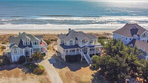 Um imóvel à beira-mar com várias casas, uma praia de areia e o oceano ao fundo.