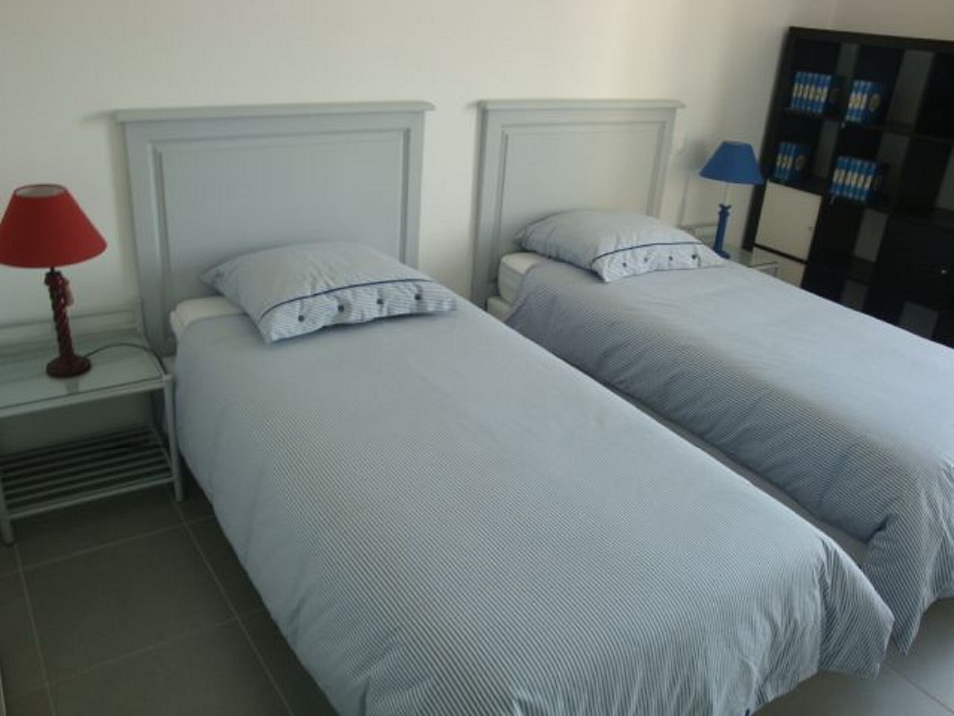 Habitación doble con dos camas, cada una con una almohada y una lámpara roja en la mesita de noche.
