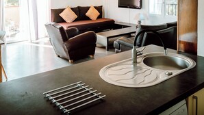 Une cuisine moderne dotée d’un lave-vaisselle encastré, d’un grand évier et d’un coin repas avec un canapé et une table.